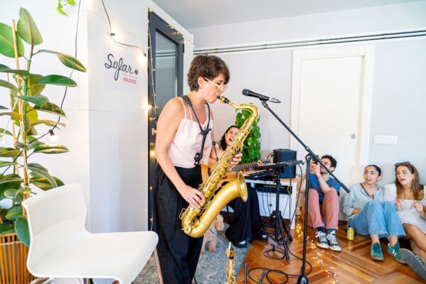 Female saxophonist performing live at a cozy indoor music event with an attentive audience.