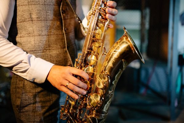 Detailed image of hands playing a golden saxophone, showcasing the intricate design and craftsmanship of the instrument.