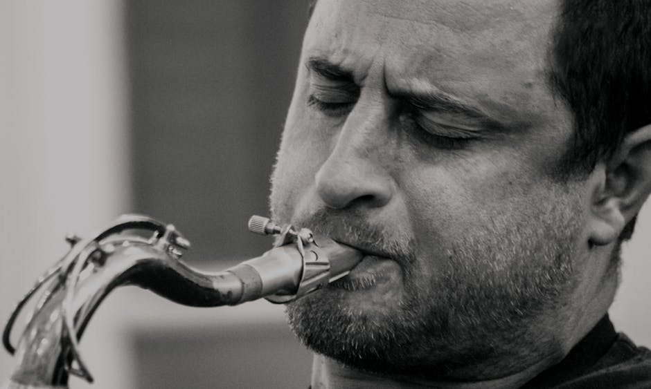 Close-up black and white portrait of a saxophonist passionately playing his instrument.