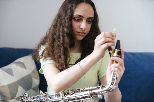 Focused woman assembling her saxophone, preparing to play music at home.