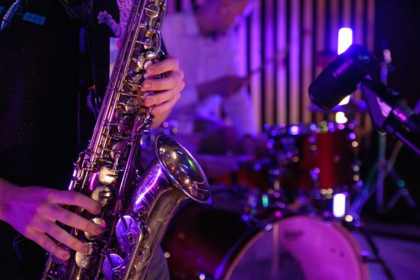 Musicians playing saxophone and drums during a vibrant live performance.