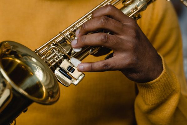 An adult musician plays a saxophone, highlighting skills and artistry.