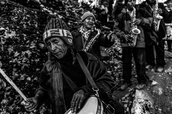 Black and white image of traditional musicians with instruments outdoors.