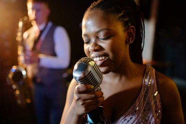 Smiling African American woman singing passionately with a jazz band.
