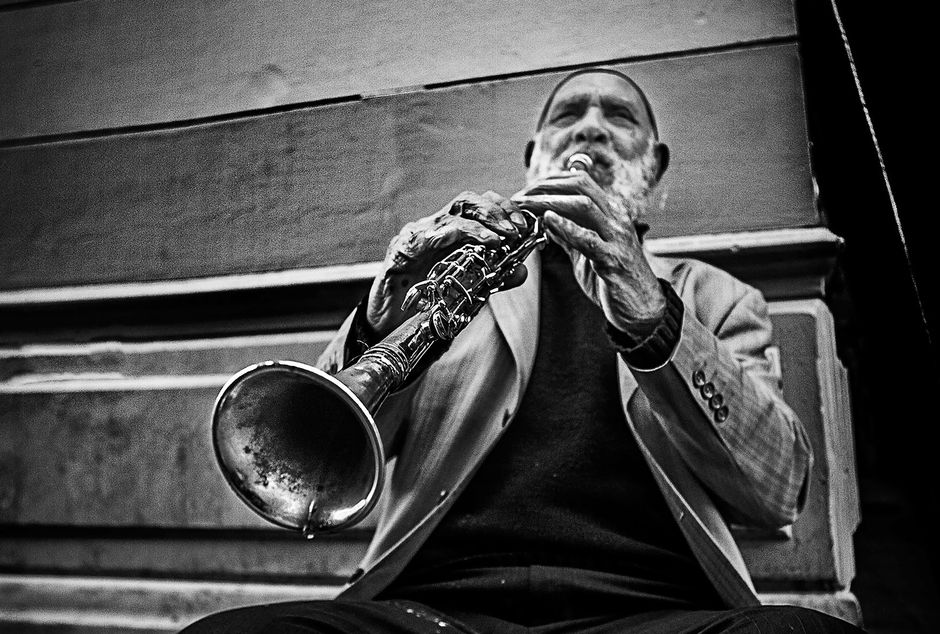 A black and white image of an elderly street musician passionately playing the clarinet.