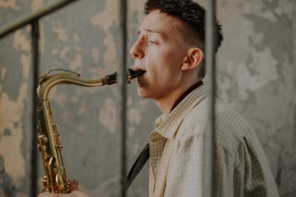 Young musician playing saxophone indoors, showcasing talent and passion.