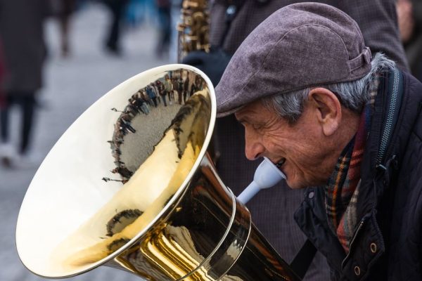 An elderly musician plays a tuba on the streets of Prague, capturing a lively street scene.